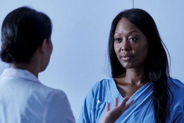 Woman patient talking to healthcare professional with image scans at the back