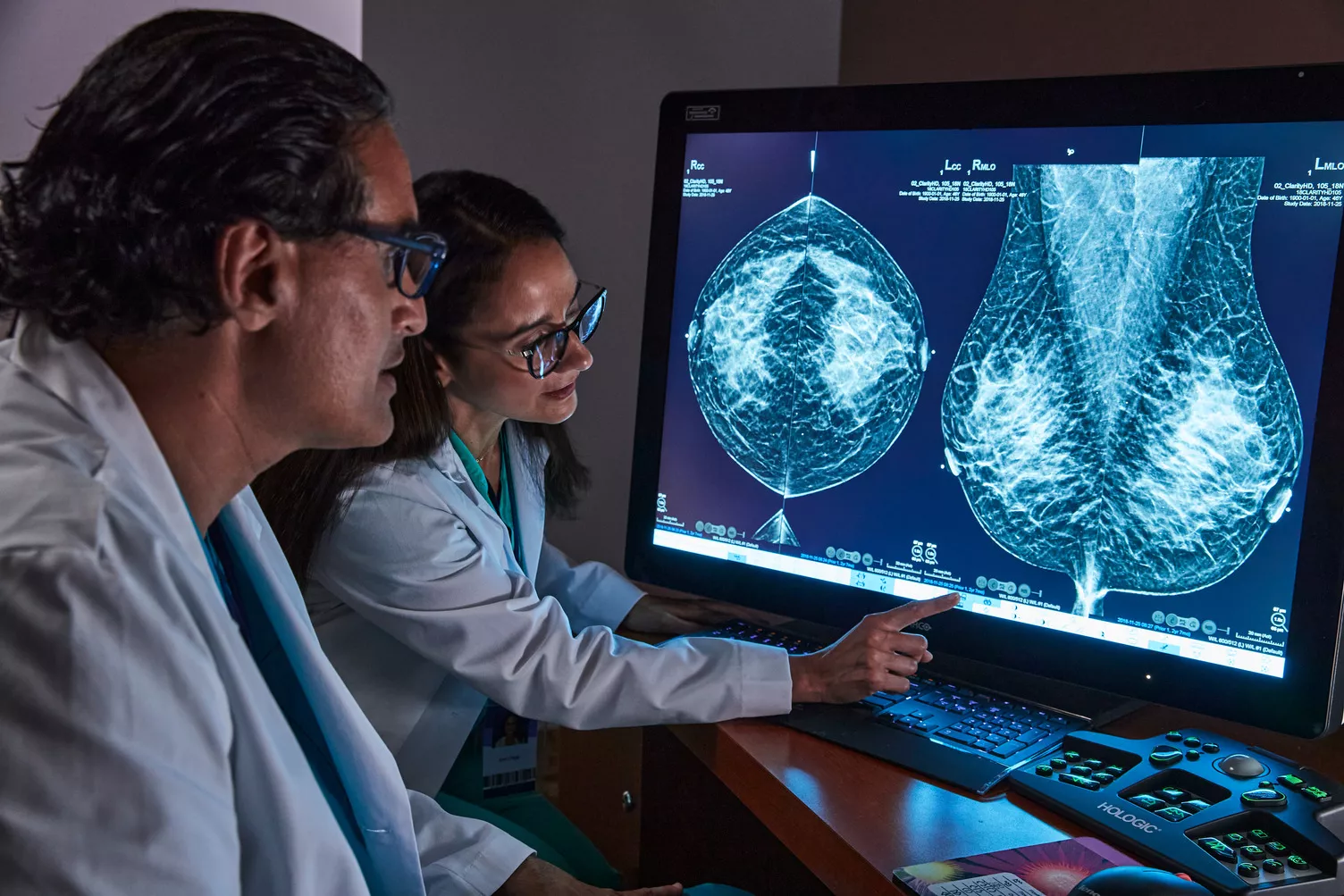 Healthcare professionals pointing to breast scan image on monitor