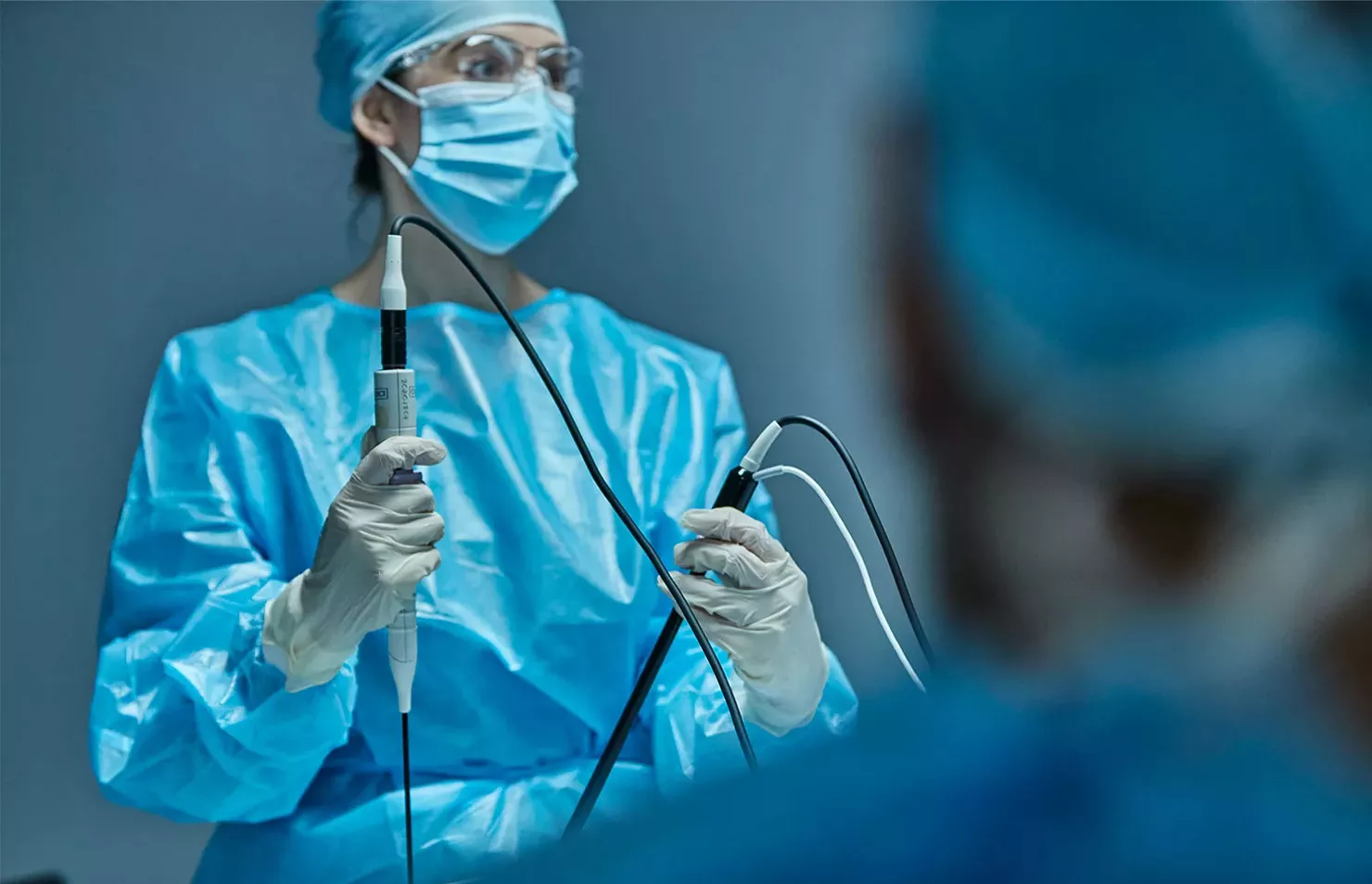 Female surgeon using medical devices in a operating room.