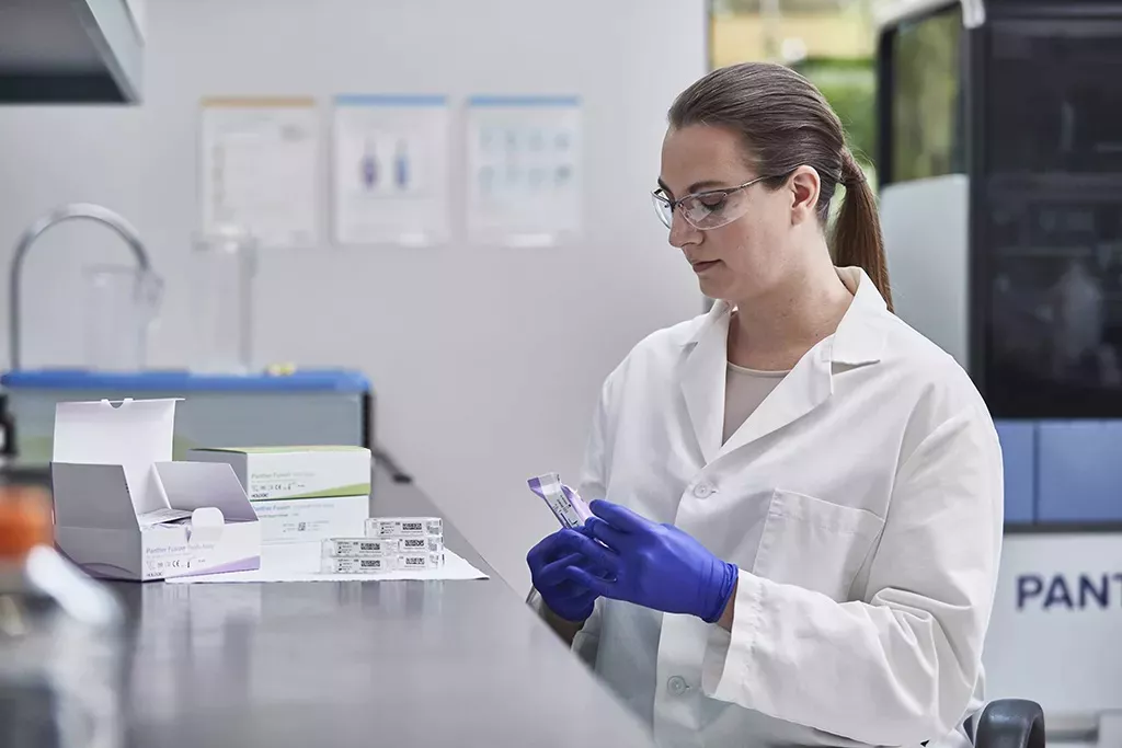 Lab technician with multiple assay boxes in lab background