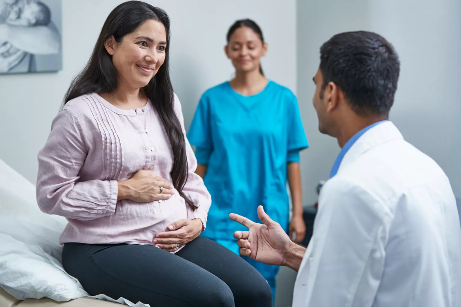 Healthcare professional talking to pregnant woman in clinic room