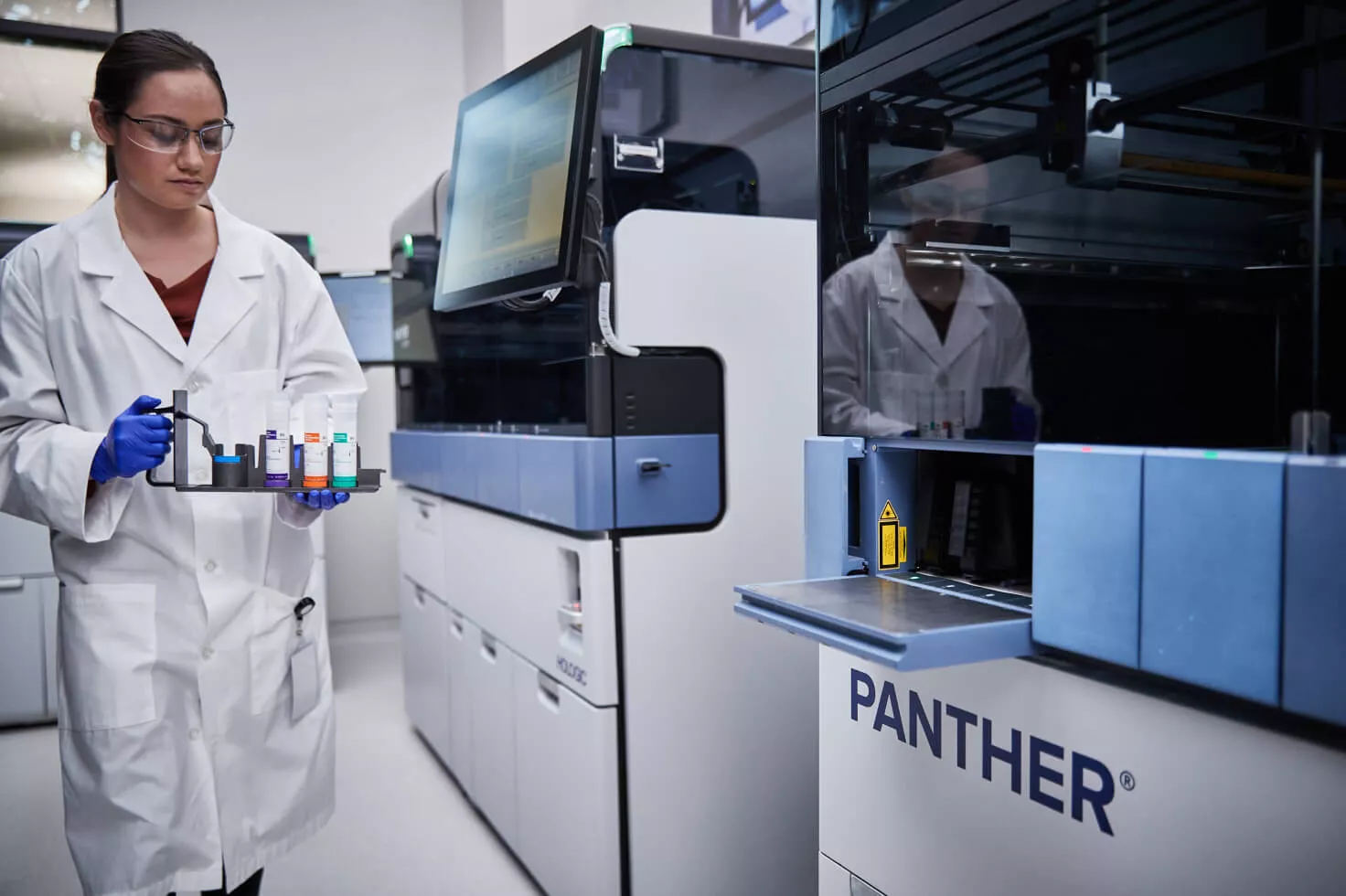 Lab technician carrying tray of vials in lab setting